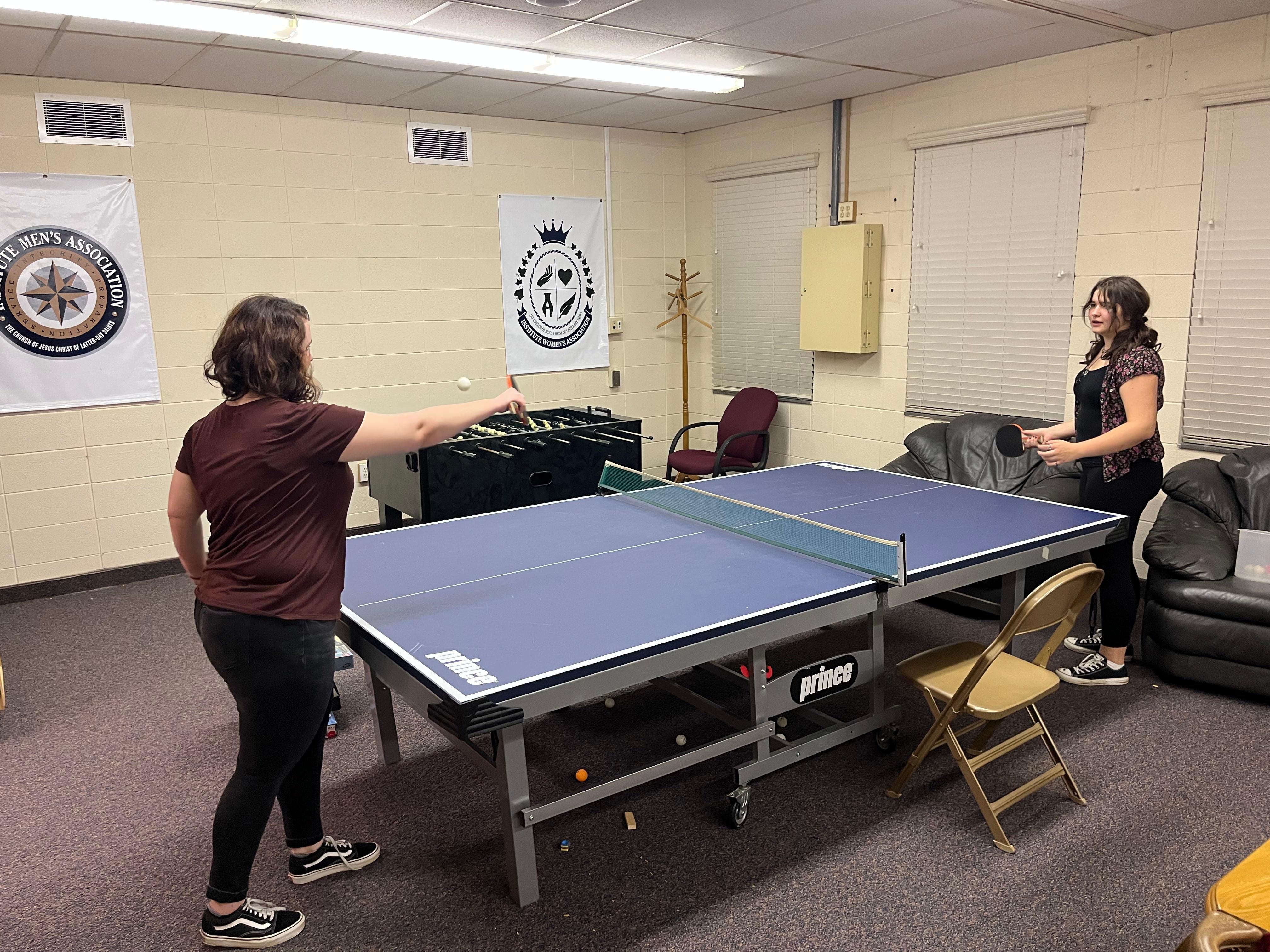 Young single adults play ping pong in the game room.