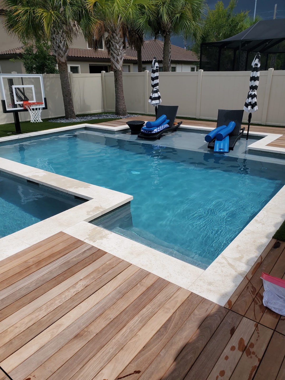 Backyard swimming pool with an attached spa, submerged lounge chairs, wood decking, and a private outdoor setting.